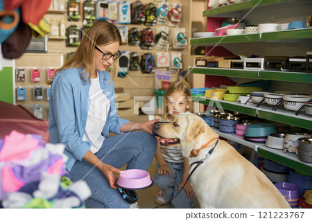 Mother and daughter choosing new plastic food plate for dog at pet shop 121223767