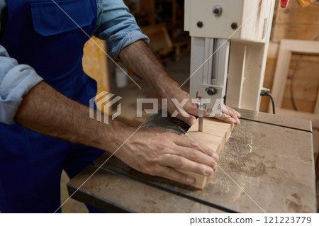 Carpentry shop worker processing woods at stationary electric jigsaw 121223779