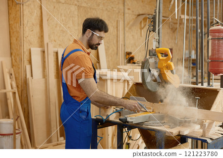 Skilled carpenter sawing wood plank using round circular saw at workbench Skilled carpenter sawing wood plank using round circular saw at workbench 121223780