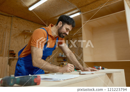 Carpenter measuring with ruler during furniture production process at workshop Carpenter measuring with ruler during furniture production process at workshop 121223794