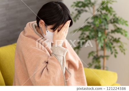戴著面具的中高級婦女在冬季房間裡頭痛 戴著面具的中高級婦女在冬季房間裡頭痛 121224386