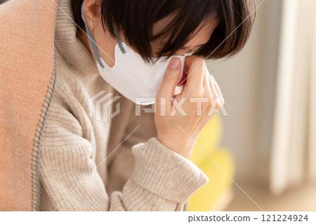 在冬季房間裡戴著口罩遮住鼻子的中高級女性 在冬季房間裡戴著口罩遮住鼻子的中高級女性 121224924