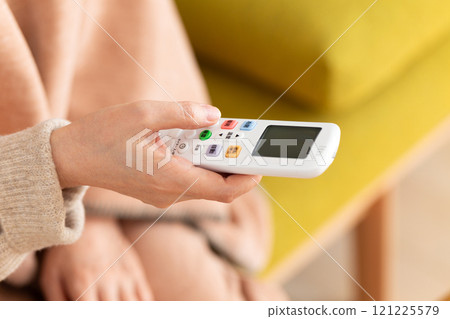 冬季客廳裡拿著空調遙控器的中高級女性 冬季客廳裡拿著空調遙控器的中高級女性 121225579