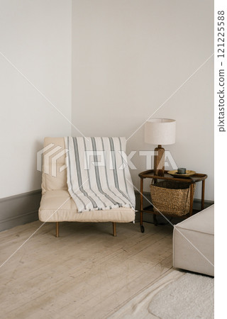 White armchair with a striped blanket, lamp on table clean and simple living room 121225588