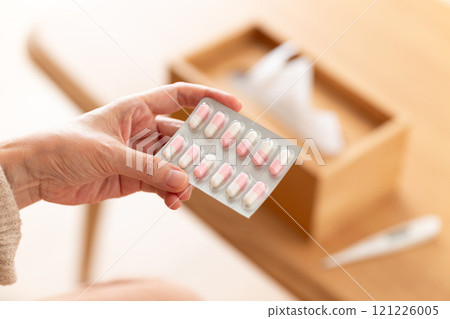 Middle-aged to senior women holding capsule medicine 121226005