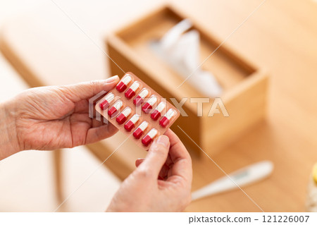 Middle-aged to senior women holding capsule medicine 121226007