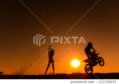 Silhouette of a man on a motorbike on the back whee Silhouette of a man on a motorbike on the back whee 121226835