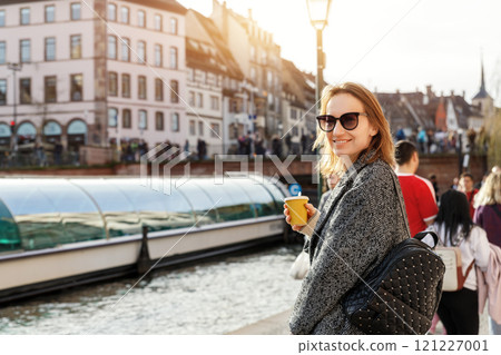Portrait young beautiful happy smiling woman wear wool tweed coat enjoy walk canal river embankment Strasbourg city street Petite France district sunny day. Stylish female person urban lifestyle Portrait young beautiful happy smiling woman wear wool tweed coat enjoy walk canal river embankment Strasbourg city street Petite France district sunny day. Stylish female person urban lifestyle 121227001