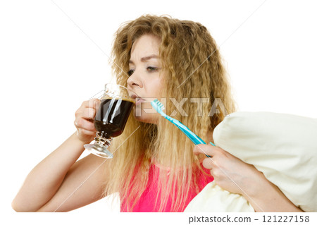Tired woman holding toothbrush and coffee Tired woman holding toothbrush and coffee 121227158
