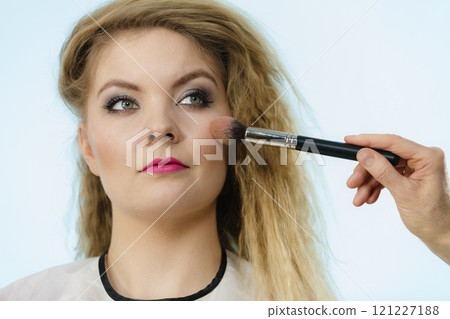 Makeup artist applying with brush rouge on female check Makeup artist applying with brush rouge on female check 121227188