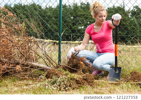 Woman digging hole in garden Woman digging hole in garden 121227358