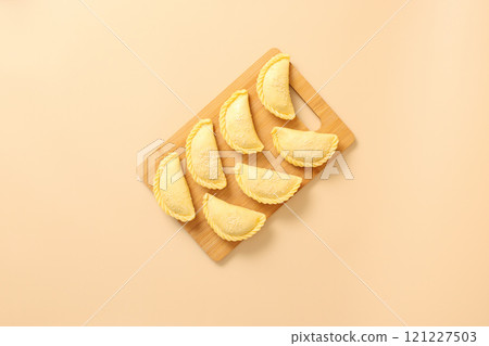 Top view on wooden board with raw pies, frozen semi-finished products bakery. 121227503