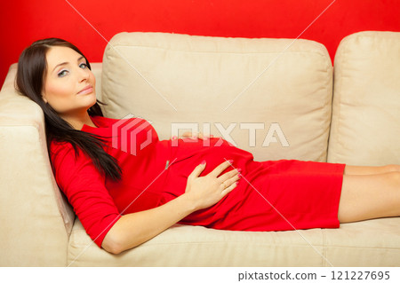 pregnant woman relaxing on sofa touching her belly pregnant woman relaxing on sofa touching her belly 121227695