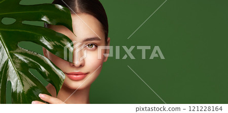 Close up woman face with green exotic leaf Close up woman face with green exotic leaf 121228164