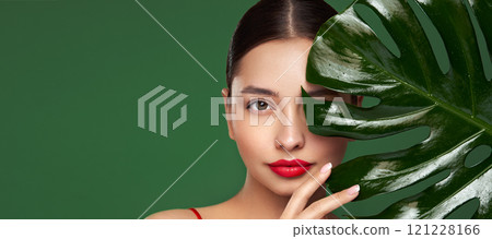 Close up woman face with green exotic leaf Close up woman face with green exotic leaf 121228166