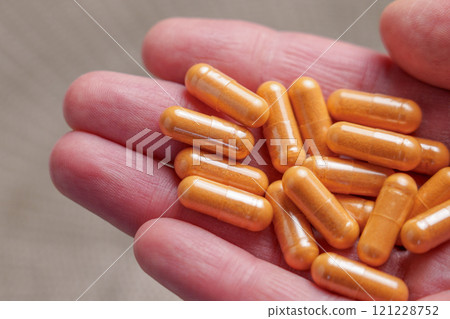 Close-up of a hand holding orange lutein capsules made with natural calendula flower extract. Herbal medicine pills Close-up of a hand holding orange lutein capsules made with natural calendula flower extract. Herbal medicine pills 121228752