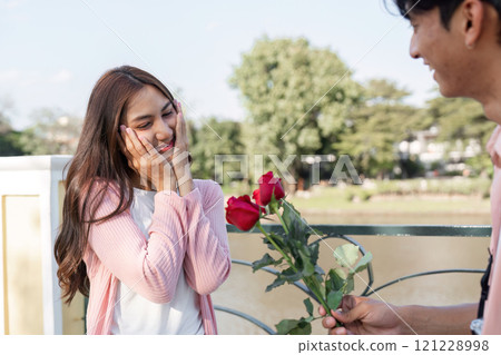 Romantic valentine surprise lover gives roses to couple by the lake capturing love in nature's embrace 121228998