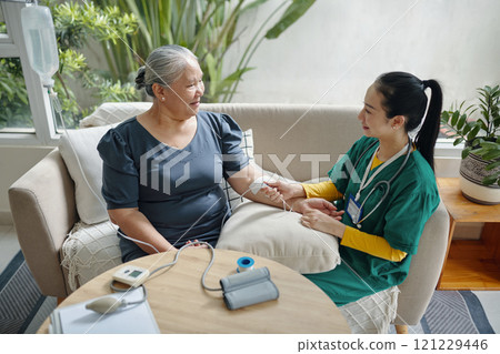 Caregiver Making IV Drip To Senior Patient Caregiver Making IV Drip To Senior Patient 121229446