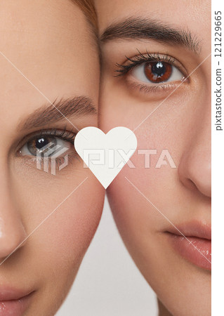 Contemporary art collage. Close-up of two faces side by side and heart with copy space, highlights their eyes and skin textures 121229665