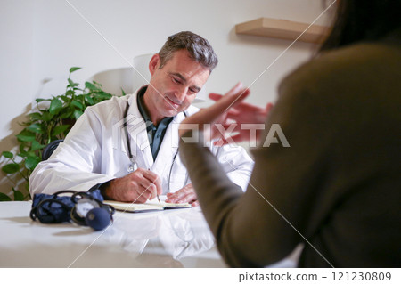 A male doctor consulting in his private office and reviewing patient reports. 121230809