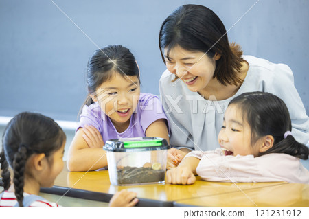 Elementary school students observing an insect cage 121231912