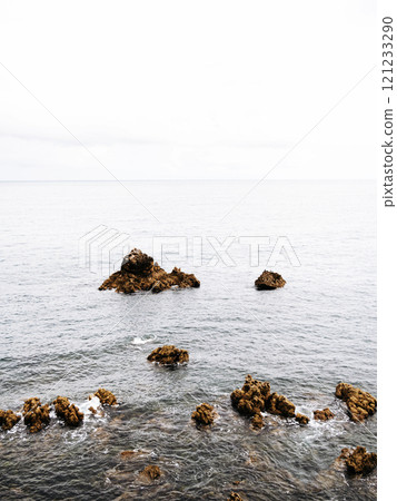 A serene seascape featuring scattered rocky formations emerging from calm ocean waters A serene seascape featuring scattered rocky formations emerging from calm ocean waters 121233290
