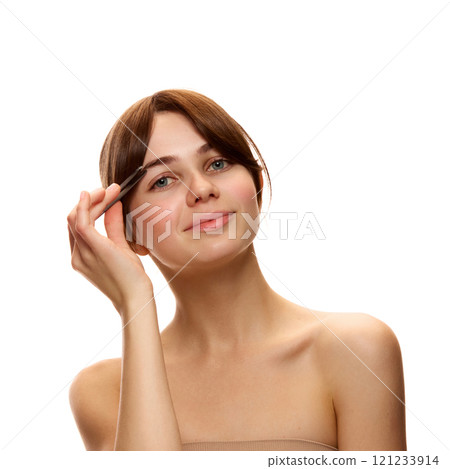 Beautiful young women without makeup, with spotless, clear, smooth skin, using tweezers for eyebrows correction against white studio background 121233914