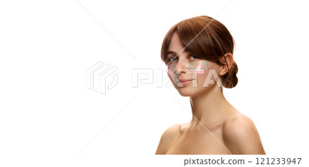 Portrait of young tender woman with spotless, clear, healthy skin, using under eye patches for refreshing look against white studio background Portrait of young tender woman with spotless, clear, healthy skin, using under eye patches for refreshing look against white studio background 121233947