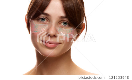 Portrait of young tender woman with spotless, clear, healthy skin, using under eye patches for refreshing look against white studio background 121233948