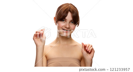 Young beautiful woman holding dental floss and smiling confidently, promoting oral hygiene and self-care against white studio background 121233957