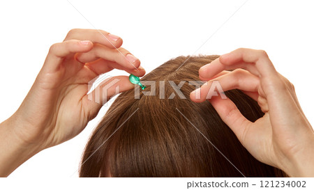 Close-up of woman applying serum capsule on her head skin, hair against white studio background. Treatment, nourishment Close-up of woman applying serum capsule on her head skin, hair against white studio background. Treatment, nourishment 121234002