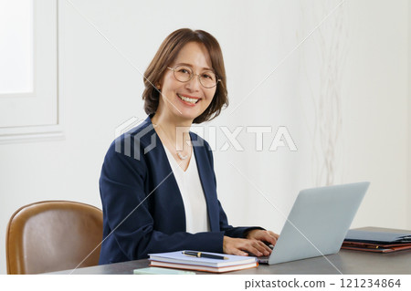 一位中年婦女在辦公桌上使用筆記型電腦工作的肖像 121234864