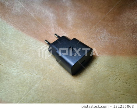 Closeup of a black super fast charging adapter on a soft background. Closeup of a black super fast charging adapter on a soft background. 121235068