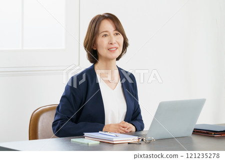 一位穿著西裝的中年婦女在辦公桌前交談 一位穿著西裝的中年婦女在辦公桌前交談 121235278