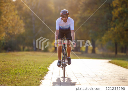 Cyclist riding along a path in a park during a sunny autumn day 121235290