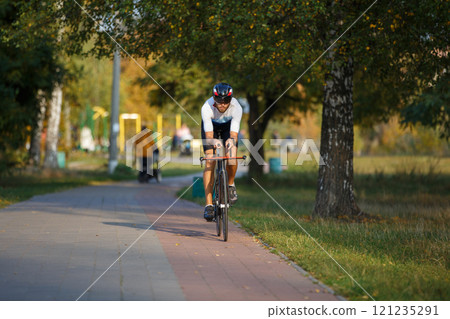 Cyclist riding along a path in a park during a sunny autumn day 121235291
