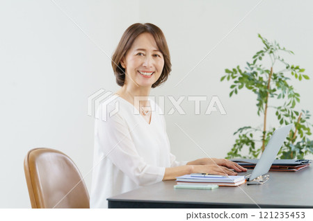 Middle-aged woman working on a computer at a desk Middle-aged woman working on a computer at a desk 121235453
