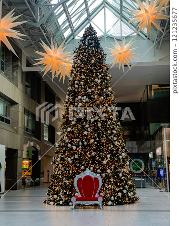 a tall Christmas tree in a shopping center with a red chair in the middle 121235677