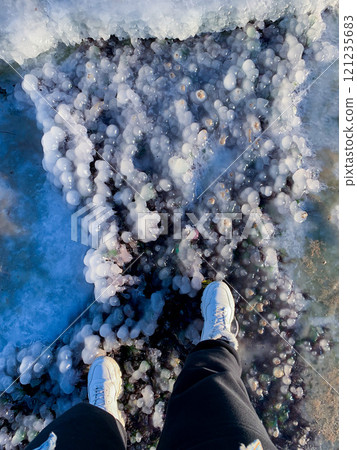 women's feet in white shoes are standing on an interestingly shaped ice women's feet in white shoes are standing on an interestingly shaped ice 121235683