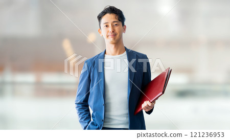 Smiling male businessman holding a binder Smiling male businessman holding a binder 121236953