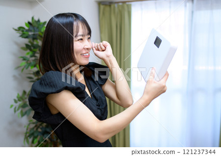 Woman happy to hold a weight scale, fist pump, weight concern, diet, success Woman happy to hold a weight scale, fist pump, weight concern, diet, success 121237344