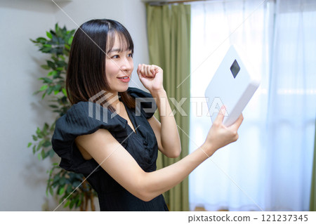 Woman happy to hold a weight scale, fist pump, weight concern, diet, success 121237345