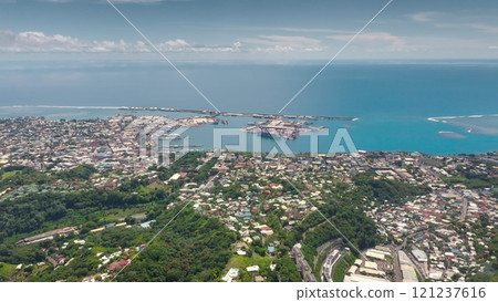 Aerial drone fly over Papeete coast, Tahiti cityscape harbor, green mountain hills, colorful village houses, streets, buildings, lush tropical vegetation against pacific ocean backdrop. Remote travel 121237616