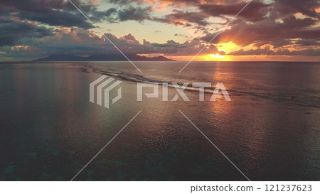 Golden sunset illuminating coral reef and Moorea island in Tahiti, French Polynesia. Aerial view showing beauty of the south pacific ocean, colorful sky and gentle waves. Natural travel background 121237623