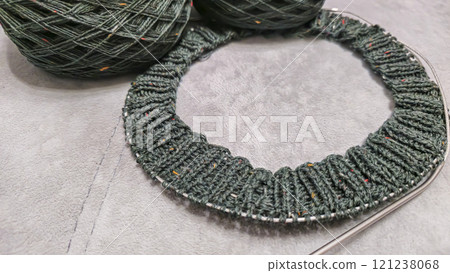 Knitted product from dark threads. Knitting a neck for a sweater with knitting needles. Knitted product from dark threads. Knitting a neck for a sweater with knitting needles. 121238068