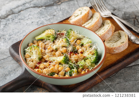 Fried broccoli chickpeas, parmesan cheese and alfredo sauce served with bread close-up on wooden board. Horizontal Fried broccoli chickpeas, parmesan cheese and alfredo sauce served with bread close-up on wooden board. Horizontal 121238381