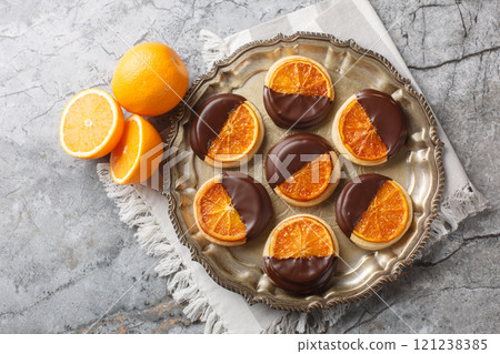 Homemade shortbread cookies with candied orange and chocolate glaze close-up in a plate. Horizontal top view 121238385