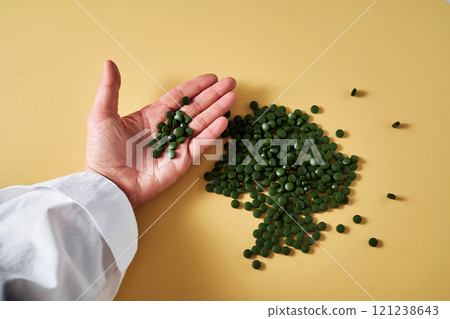 Superfood chlorella in tablet form in a woman's hand. 121238643