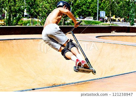 Young man practicing Scootering (Freestyle Scootering) in the new SkatePark of the central park of Igualada, Barcelona, Spain 121238947