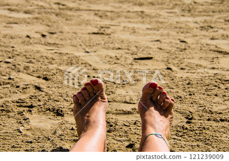 Woman feet in the sand with nails painted red 121239009